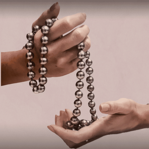 Manos de mujer sujetando un collar de perlas negras de Tahití
