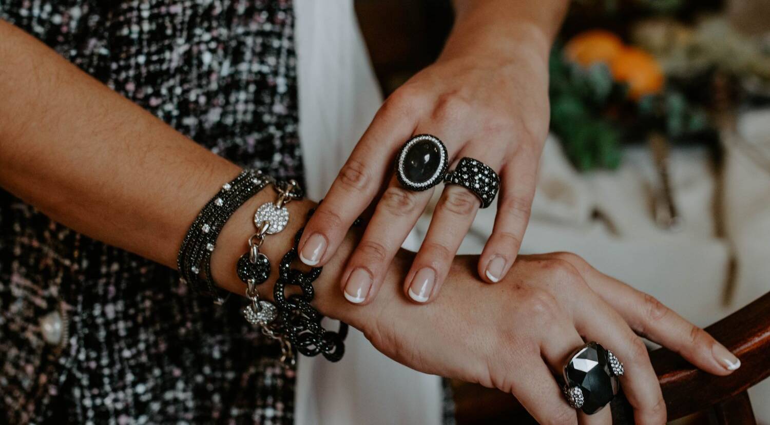 Layering realizado con la combinación de pulseras de color negro y diversos anillos