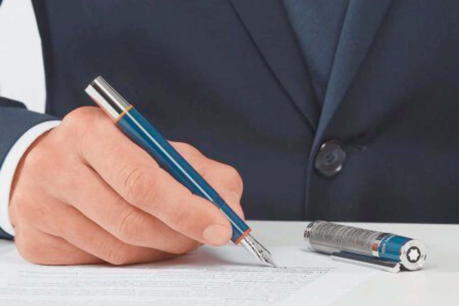 Hombre, escribiendo con una pluma estilográfica sobre un documento