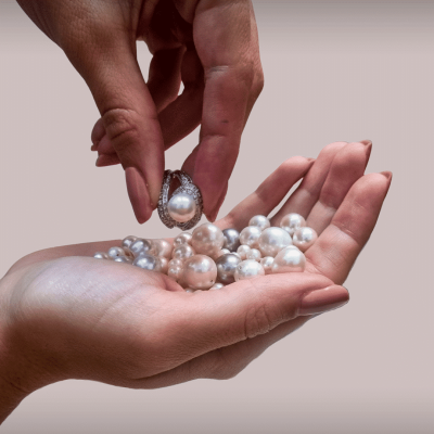 Mano enseñando un anillo de oro blanco con diamantes y perla australiana Las manos de una mujer muestran una sortija de oro blanco con diamantes y perla australiana