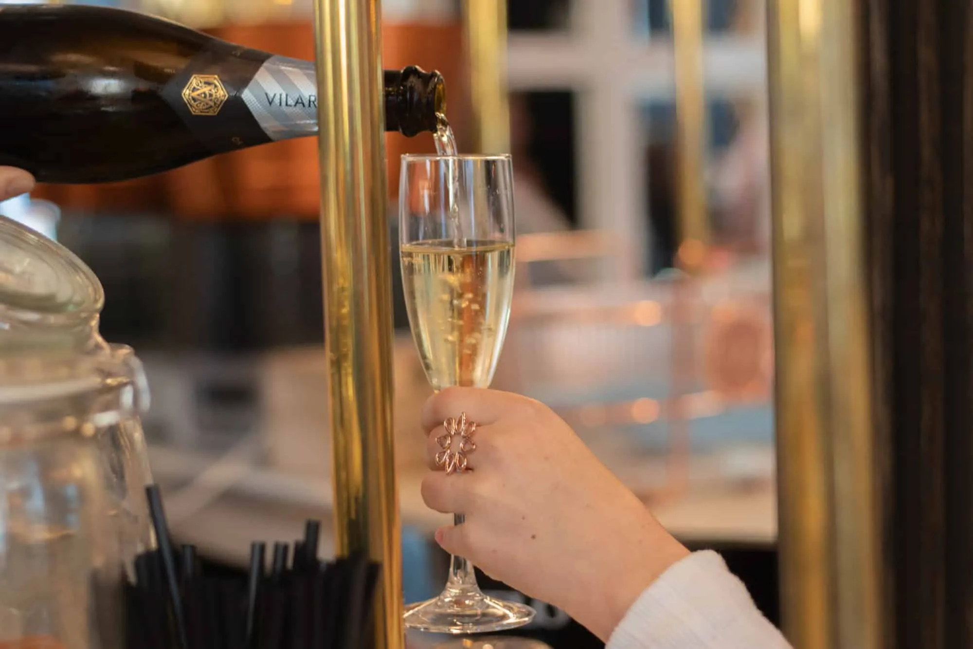 Champagnerglas, das von einer Hand mit einem Ring gehalten wird meraki
